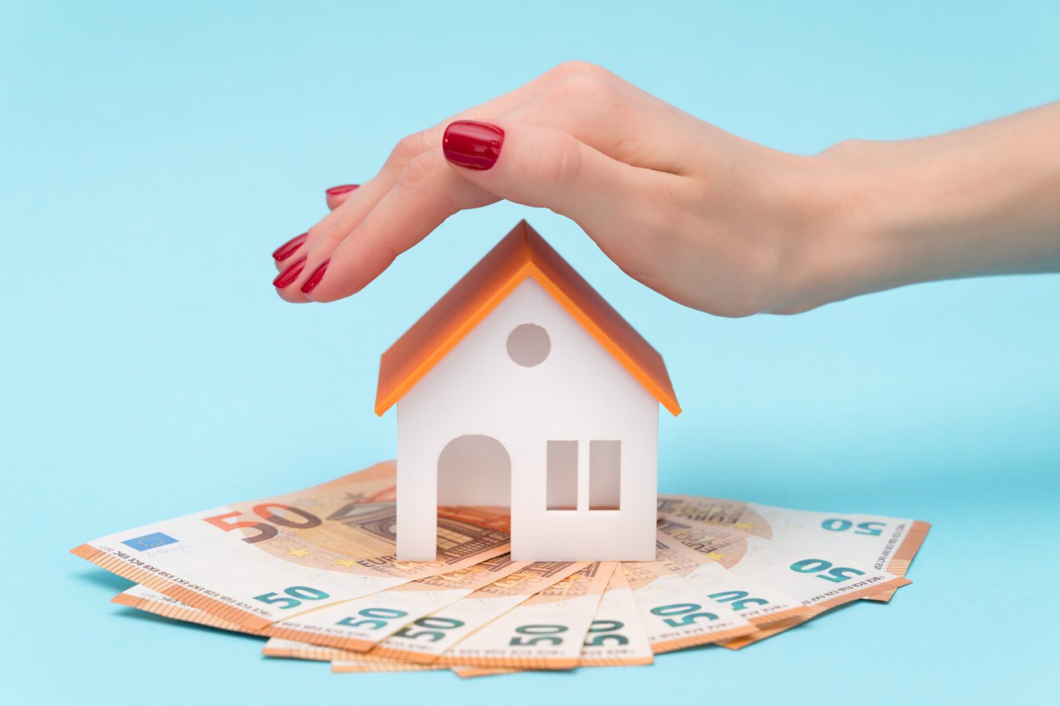 a woman's hand over the roof of the toy house on a blue background with free space for text